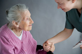 Trabajador social dando la mano a una anciana